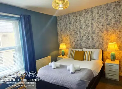 a bedroom with two beds and two lamps and a window at Harcourt by Prestige Properties SA in Workington