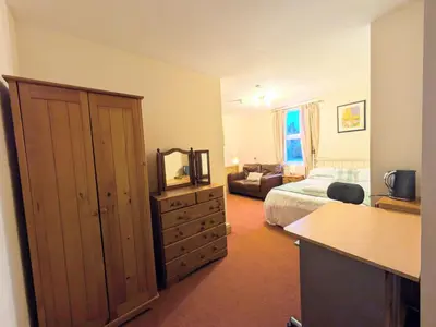 a bedroom with a bed and a dresser with a mirror at Ensuite rooms, self-catering in shared kitchens in Dumfries