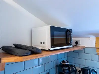 a microwave sitting on top of a wooden shelf at Workington Haven - 3 Bed Home in Workington