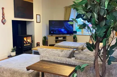 a living room with a couch and a table and a tv at Secluded Hot Tub, Pool, Escape in Bootle
