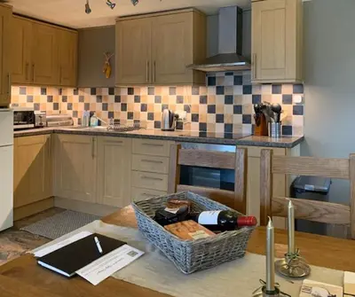a kitchen with a table with a bottle of wine at The Gower Cottages in Moffat