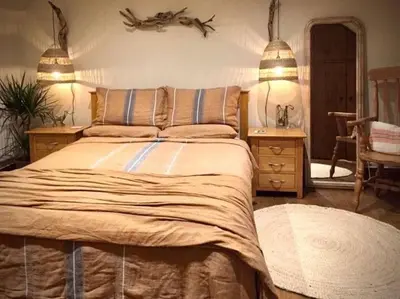 a bedroom with a bed and a table and a mirror at The Gower Cottages in Moffat