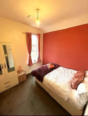 a bedroom with a red wall with a bed and a window at 5BR House w Garden Near Stadium in Moffat