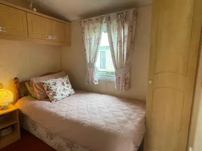 a small bedroom with a bed and a window at Grannys Vintage Coastal Caravan in Kippford
