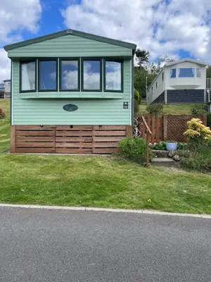 a green tiny house on top of a yard at Grannys Vintage Coastal Caravan in Kippford