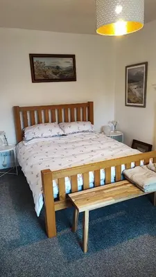 a bedroom with a wooden bed and a wooden bench at Cosy cottage near Thornhill in Closeburn