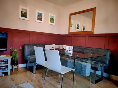 a dining room with a mirror and white chairs at Cosy cottage near Thornhill in Closeburn