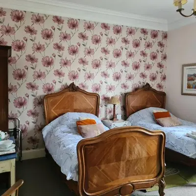 two beds in a bedroom with flowers on the wall at 95 St Mary Street in Kirkcudbright