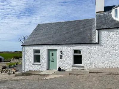 a white brick building with a green door at The Cheese Loft in Drummore
