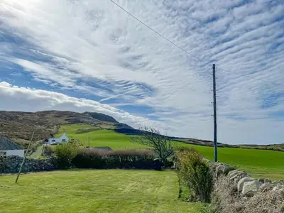 a field with a fence and a house in the distance at The Cheese Loft in Drummore