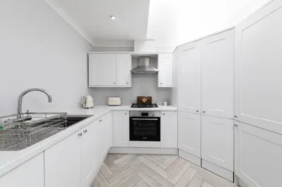 a white kitchen with white cabinets and a sink at Stunning 2 bedroom Apartment in Central Keswick in Keswick