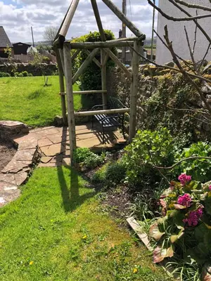a garden with a wooden pergola and some flowers at Pottery Cottage - close to the Lake District in Skelton