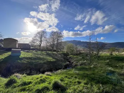 a grassy field with a barn in the background at Mountain View Shepherds Hut in Penrith