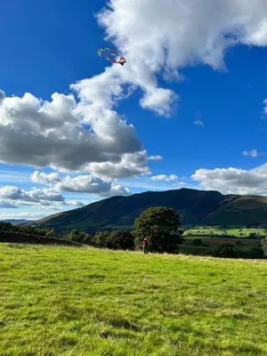 a person is flying a kite in a field at Mountain View Shepherds Hut in Penrith
