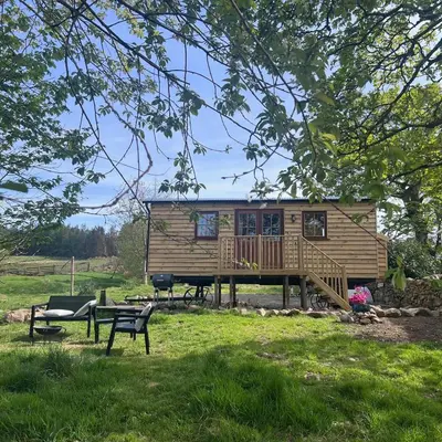 a cabin in a park with a deck and a bench at Mountain View Shepherds Hut in Penrith