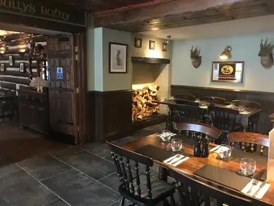 a restaurant with wooden tables and chairs and a bar at The Clachan Inn in Dalry