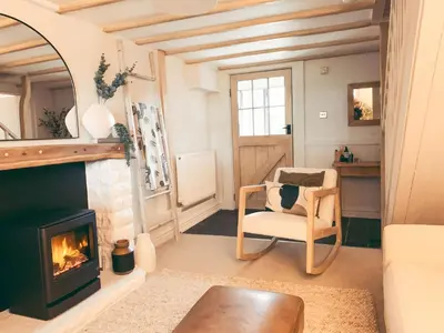 a living room with a fireplace and a chair at North Lakes - The Byre Holiday Cottage in Penrith