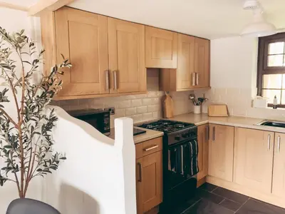 a kitchen with wooden cabinets and black appliances at North Lakes - The Byre Holiday Cottage in Penrith