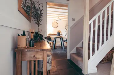 a hallway with a staircase with a table and a dining room at North Lakes - The Byre Holiday Cottage in Penrith