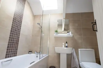 a bathroom with a sink and a tub and a toilet at North Lakes - The Byre Holiday Cottage in Penrith