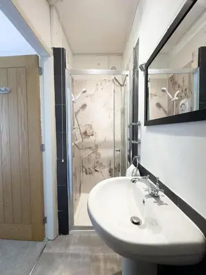 a bathroom with a white sink and a shower at Spacious 4-Bed Lake District Getaway for Groups in Mealsgate