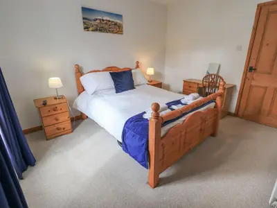 a bedroom with a wooden bed and a wooden door at Capella Cottage in Keswick