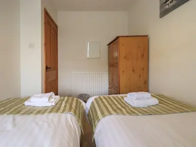 two beds in a room with towels on them at Capella Cottage in Keswick