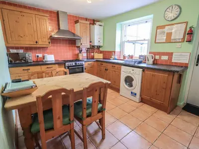 a kitchen with a table and a washing machine at Capella Cottage in Keswick