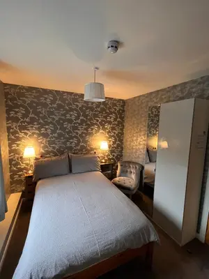 a bedroom with a large bed and a wall at Tigh-Na-Mara Hotel in Sandhead