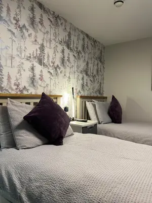 a bedroom with two beds with purple pillows and a wallpaper at Tigh-Na-Mara Hotel in Sandhead
