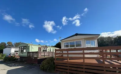 a home with a fence and a house at Creebridge Caravan Park in Newton Stewart