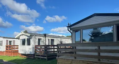 a white house with a wooden fence next to it at Creebridge Caravan Park in Newton Stewart