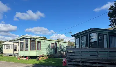 a green and white house with a black roof at Creebridge Caravan Park in Newton Stewart