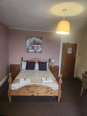a bedroom with a wooden bed with two pillows at LSO Guest House in Dumfries