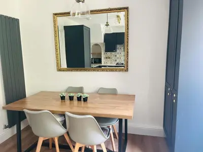 a dining room table with chairs and a mirror at Lovely spacious home near station in Moffat