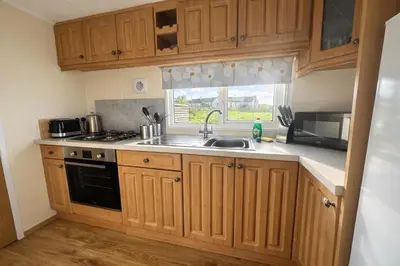 a kitchen with wooden cabinets and a sink and a window at Stunning Sea View - Farm Stay - Kilchoman 9 in Stranraer