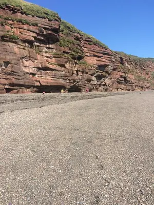 a large rock wall with a mountain in the background at High House Cottage - A traditional home from home in St Bees