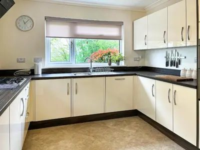 a kitchen with white cabinets and a window at Autumn Leaves in Keswick