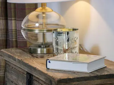 a book on a wooden table with a lamp and a glass container at The Stables in Thornhill