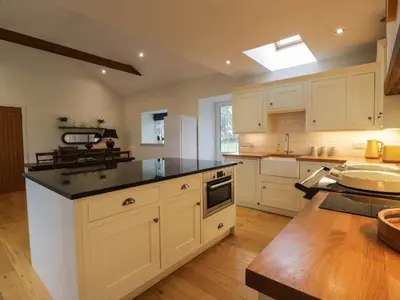 a kitchen with white cabinets and a black counter top at The Stables in Thornhill