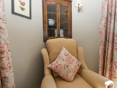 a chair with a pillow in a room with a window at Osprey Cottage in Ambleside