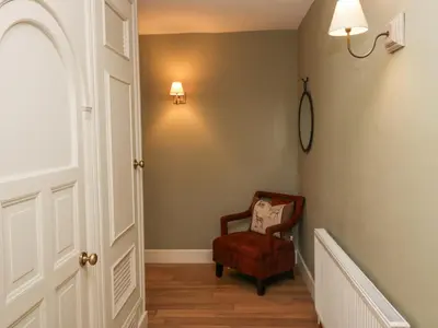 a hallway with a chair and a light on the wall at Osprey Cottage in Ambleside