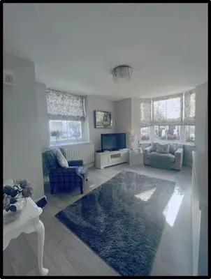 a living room with a blue rug and a tv at Coastal Cwtch in Moffat