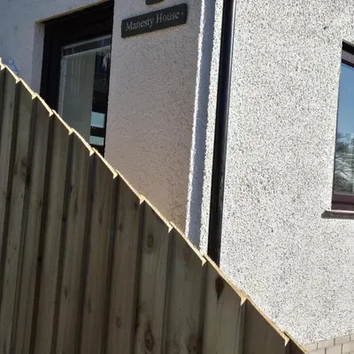 a wooden fence next to a building with a sign on it at Manesty House - Rooms only - no kitchen-living in Keswick