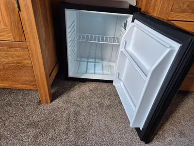 an empty refrigerator with its door open next to a cabinet at Manesty House - Rooms only - no kitchen-living in Keswick