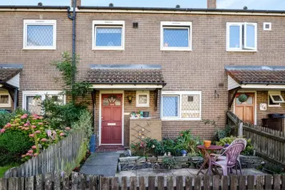 a brick house with a red door and a wooden fence at Guild Close in Moffat