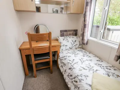 a small bedroom with a desk and a bed and a mirror at Cates Cozy Cabin in Carlisle