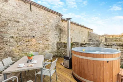 a hot tub on a patio with a table and chairs at 3 Bed in Caldbeck oc-h30704 in Caldbeck