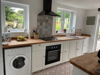 a kitchen with a washer and dryer in it at Glencairn Cottage in Moffat