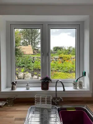a kitchen window with a sink and a view of a garden at Glencairn Cottage in Moffat